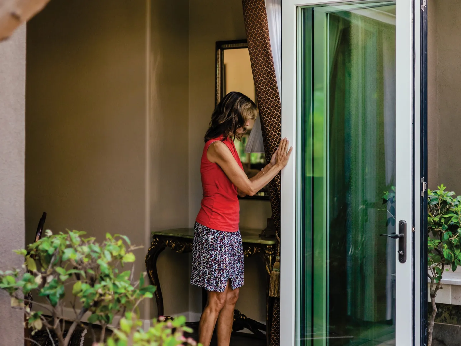 Woman sliding bi-fold doors open to connect inside and outside space.