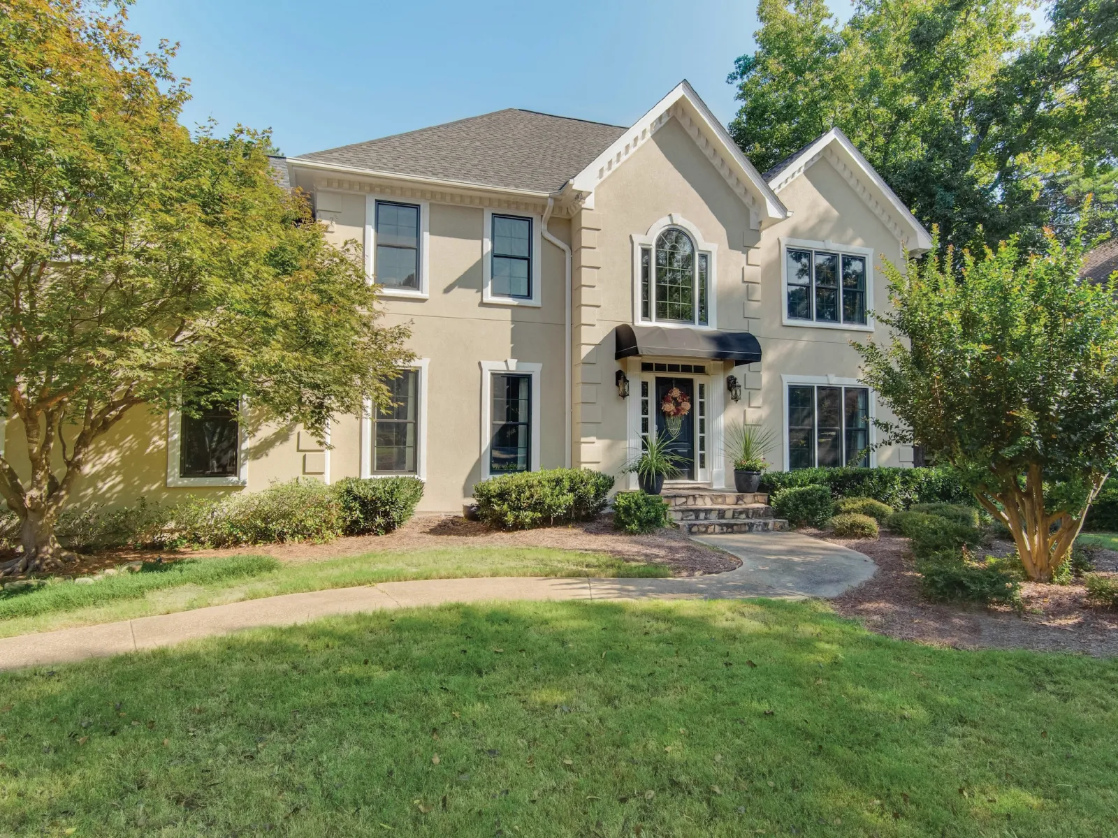 Charming suburban home with lush landscaping and inviting entrance area on a sunny day.