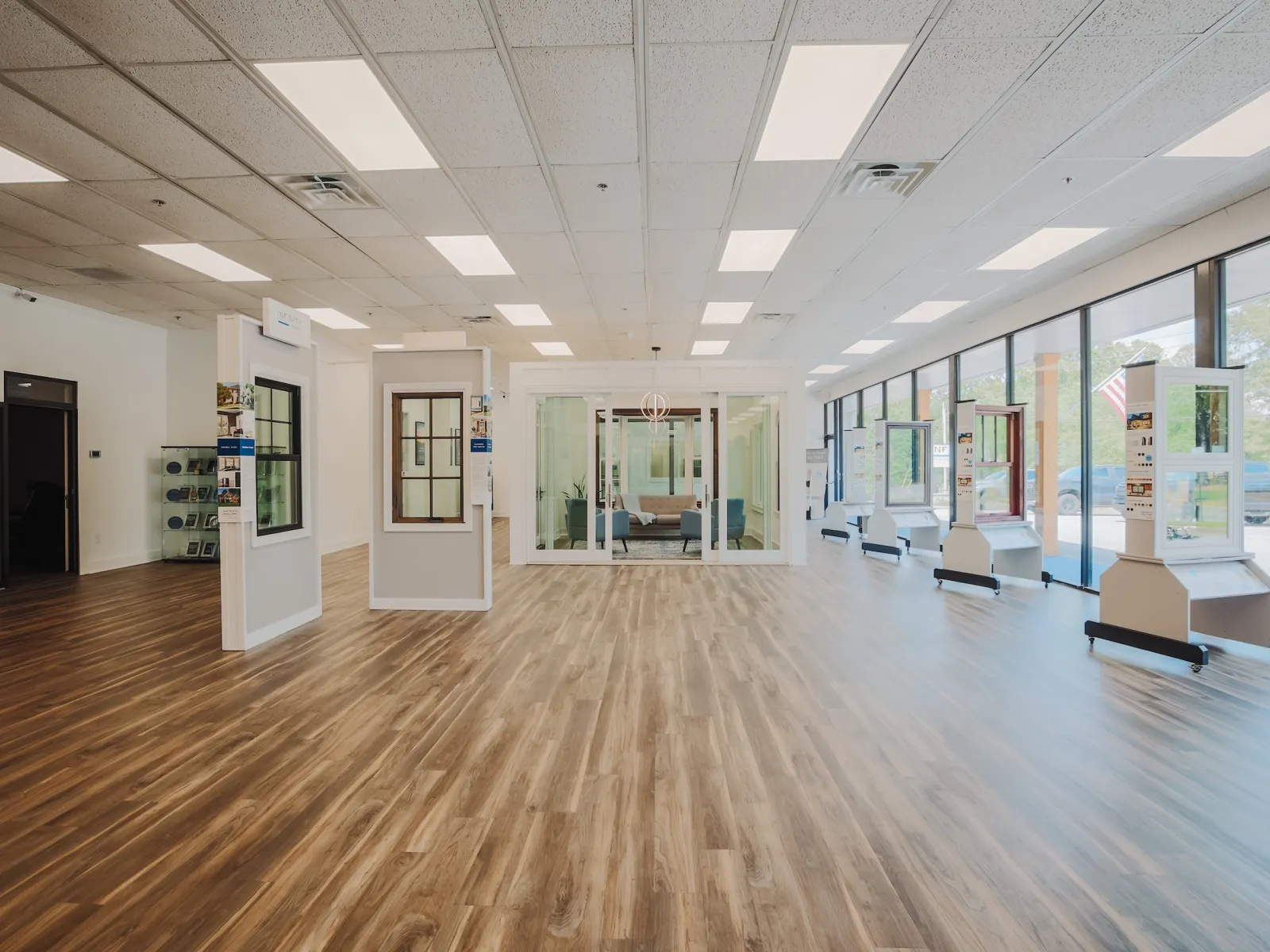 Bright showroom with wood flooring, window displays, and glass partition in a modern commercial space.