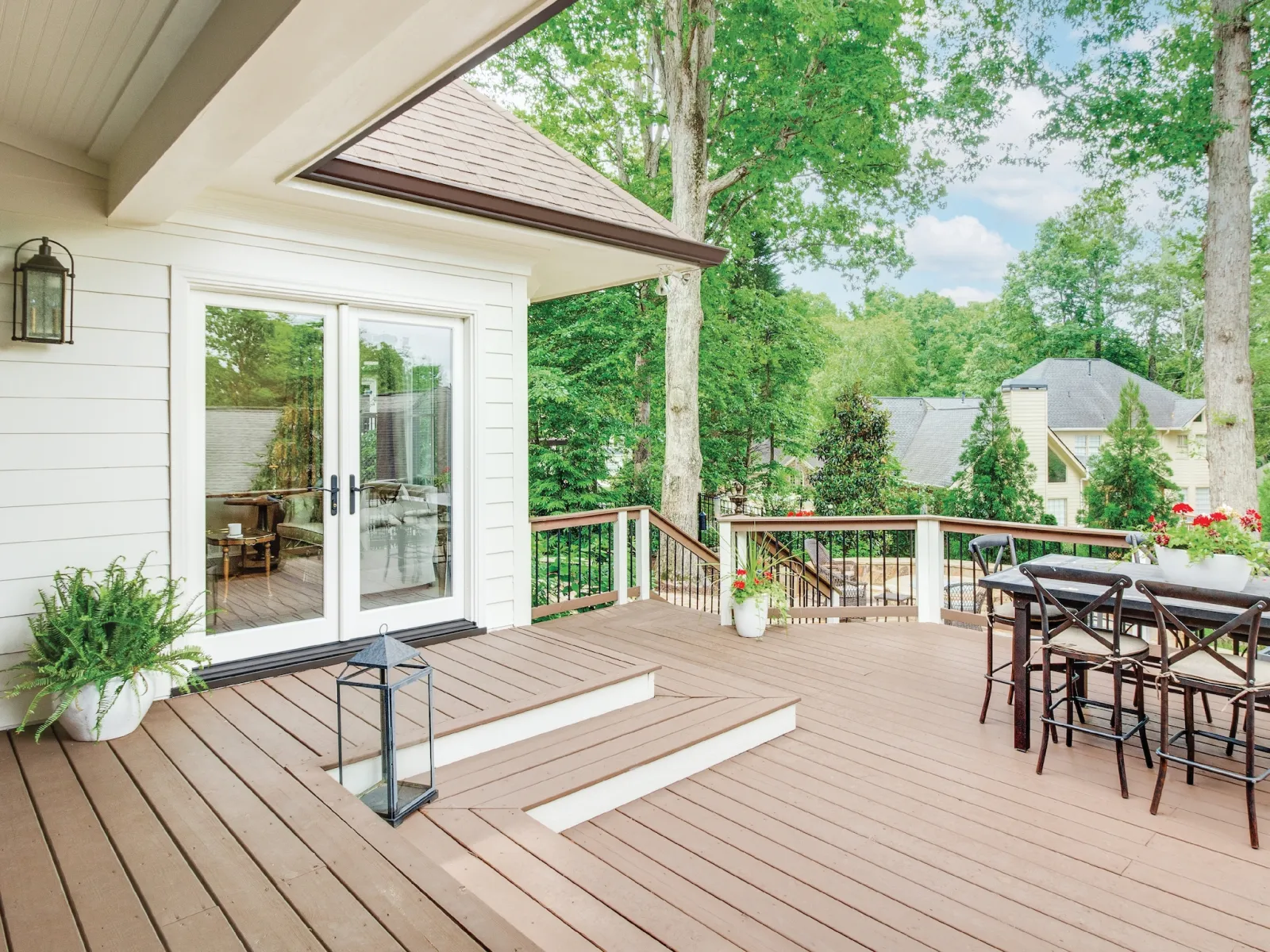A deck with a white fiberglass French door on the side of the white home