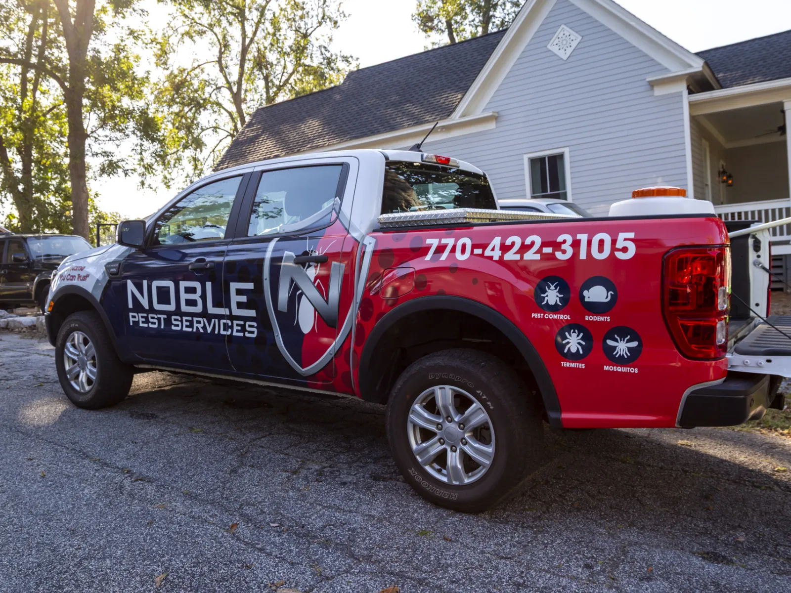 Noble Pest Services truck parked outside a house with company logo and contact number 770-422-3105 visible