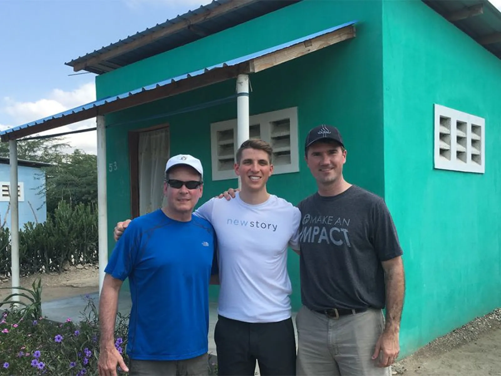 Mark Seeley (CEO of Intellinet), Frank Bell (founder of Intellinet), and Brett Hagler (Founder of NewStory Charity) in front of a new house as a part of Intellinet's pledge to build the NET, value created from OAKS Advisory Group