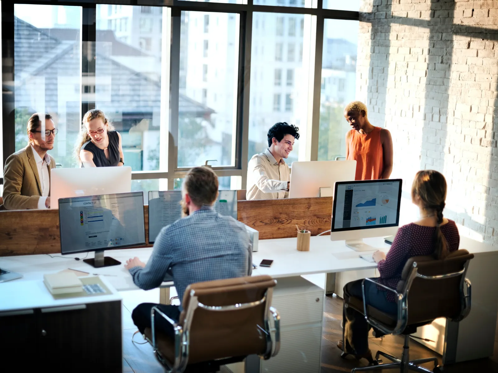 a group of people sitting around a table with computers