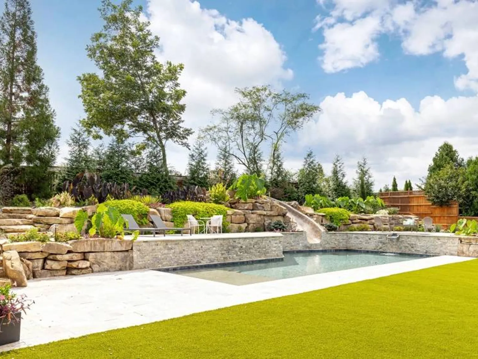a pool with a stone wall and trees in the background