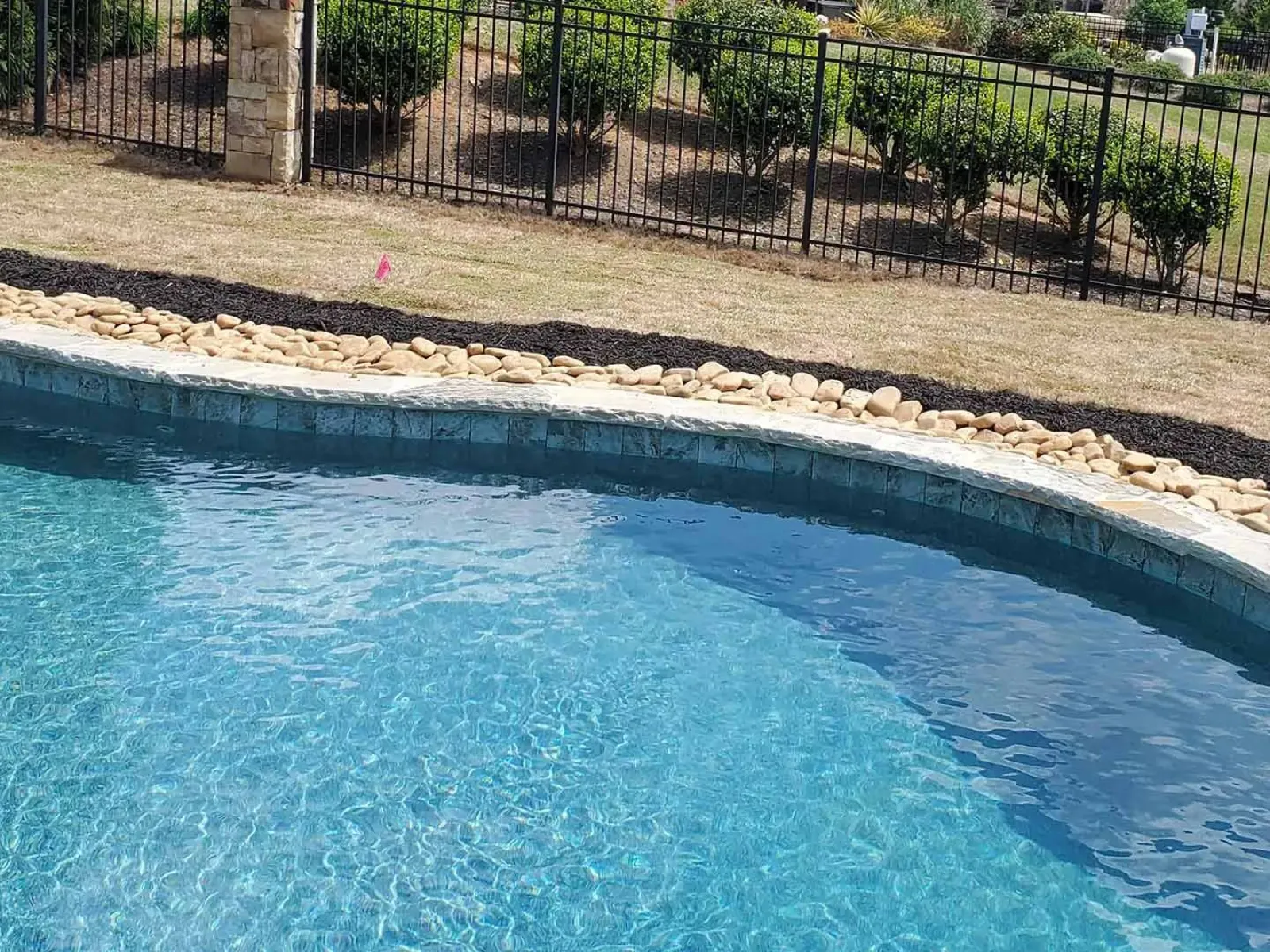 a pool with rocks and a fence around it