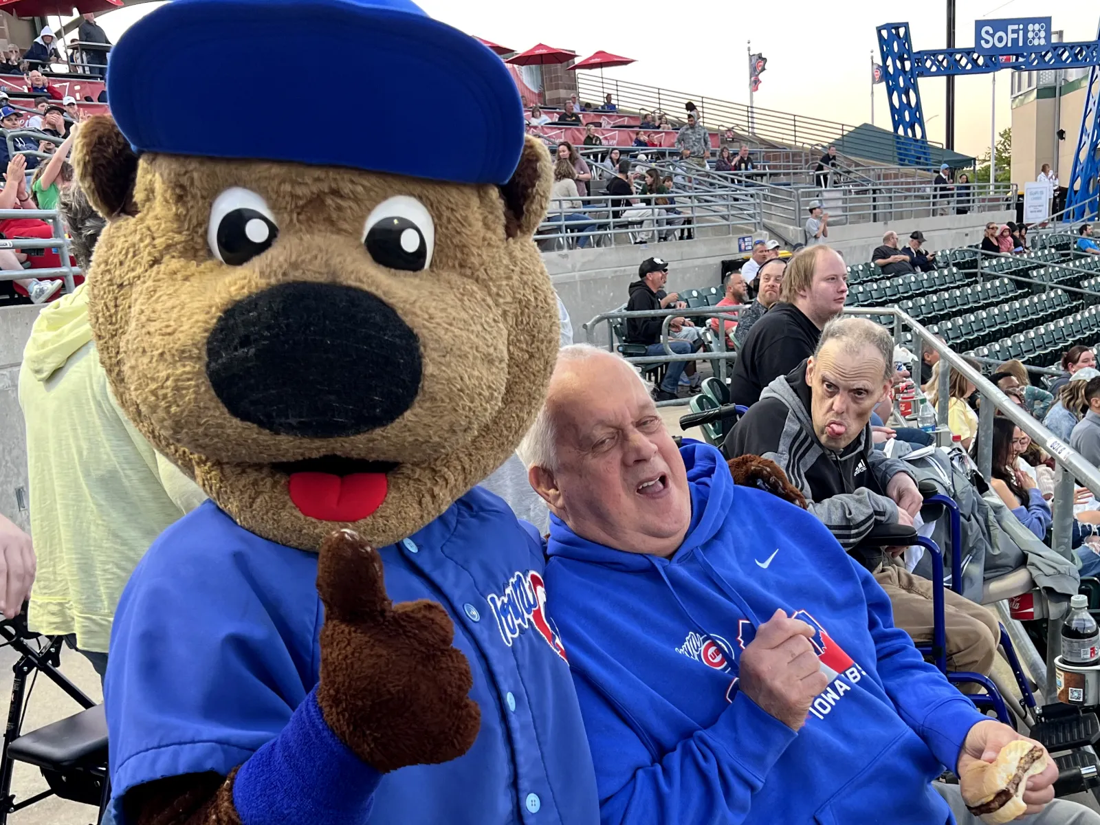 a person sitting in a stadium with a mascot