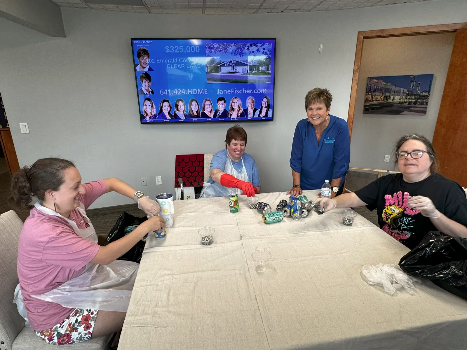 a group of people sitting around a table with a television in the background
