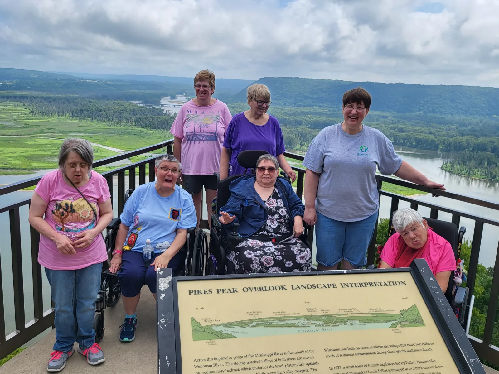 a group of people posing for a photo on a balcony overlooking a valley