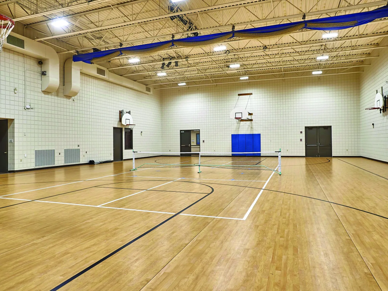 Empty gymnasium with basketball hoops and a badminton court setup.