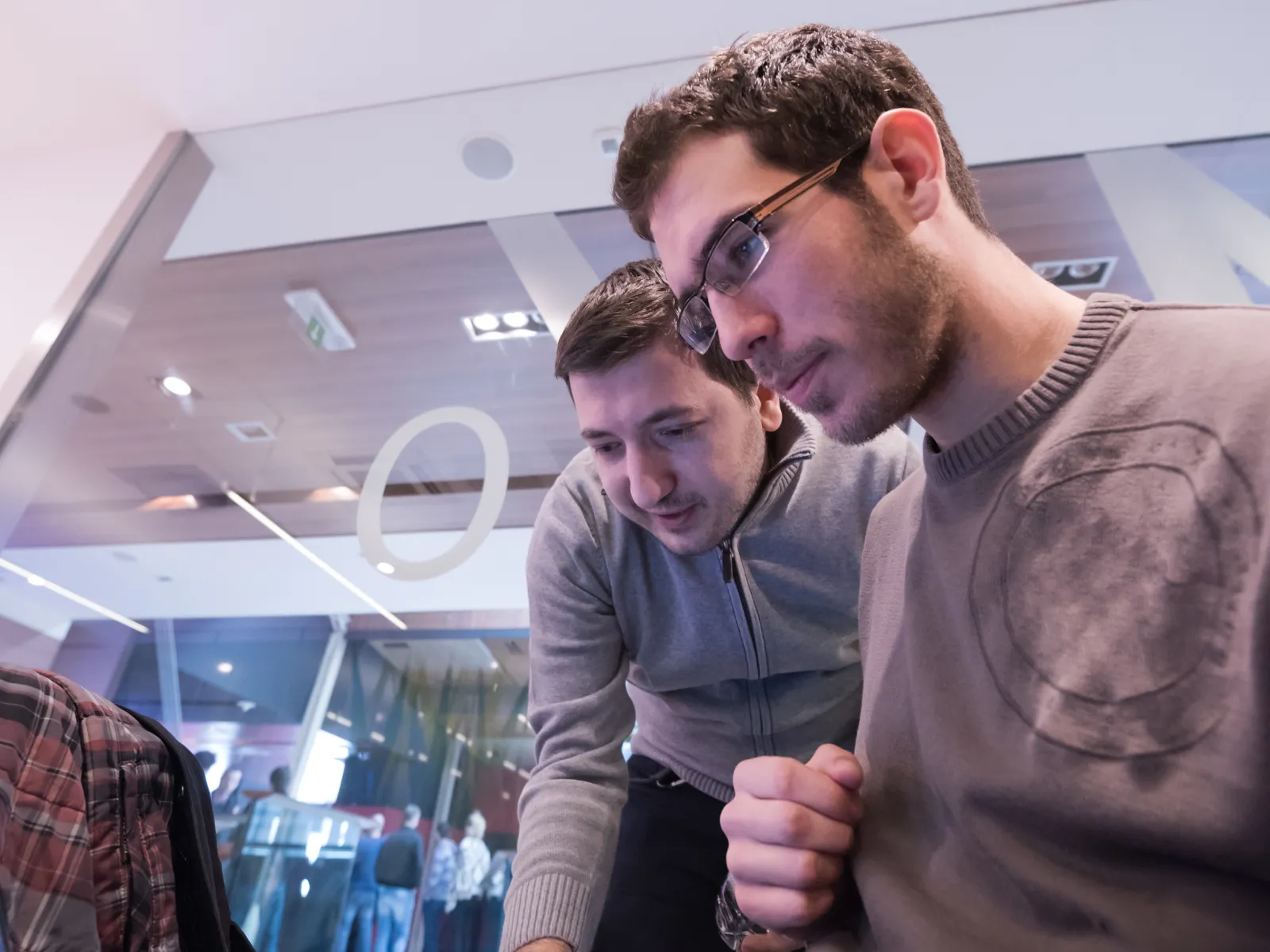 Two men collaborating on a laptop in a modern workspace, focused on their task.