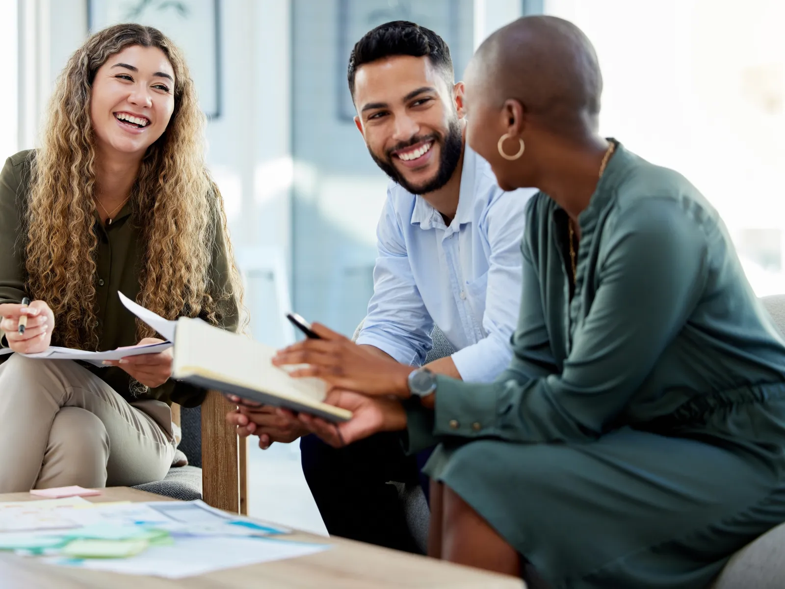 Three diverse professionals collaborate and discuss ideas in a modern office setting.