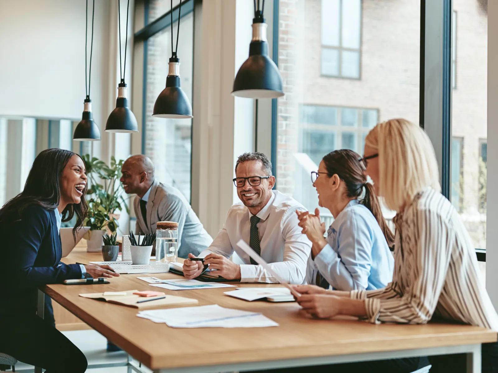 Diverse team collaborating in a modern office with large windows and a warm atmosphere.