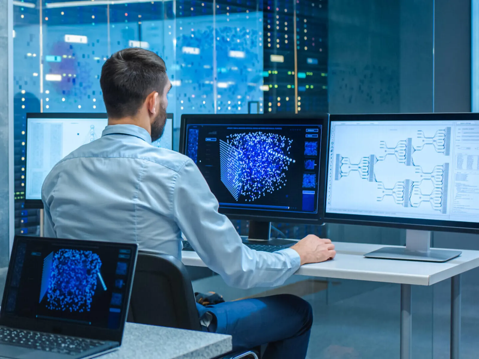 a man sitting at a desk with a laptop and a computer