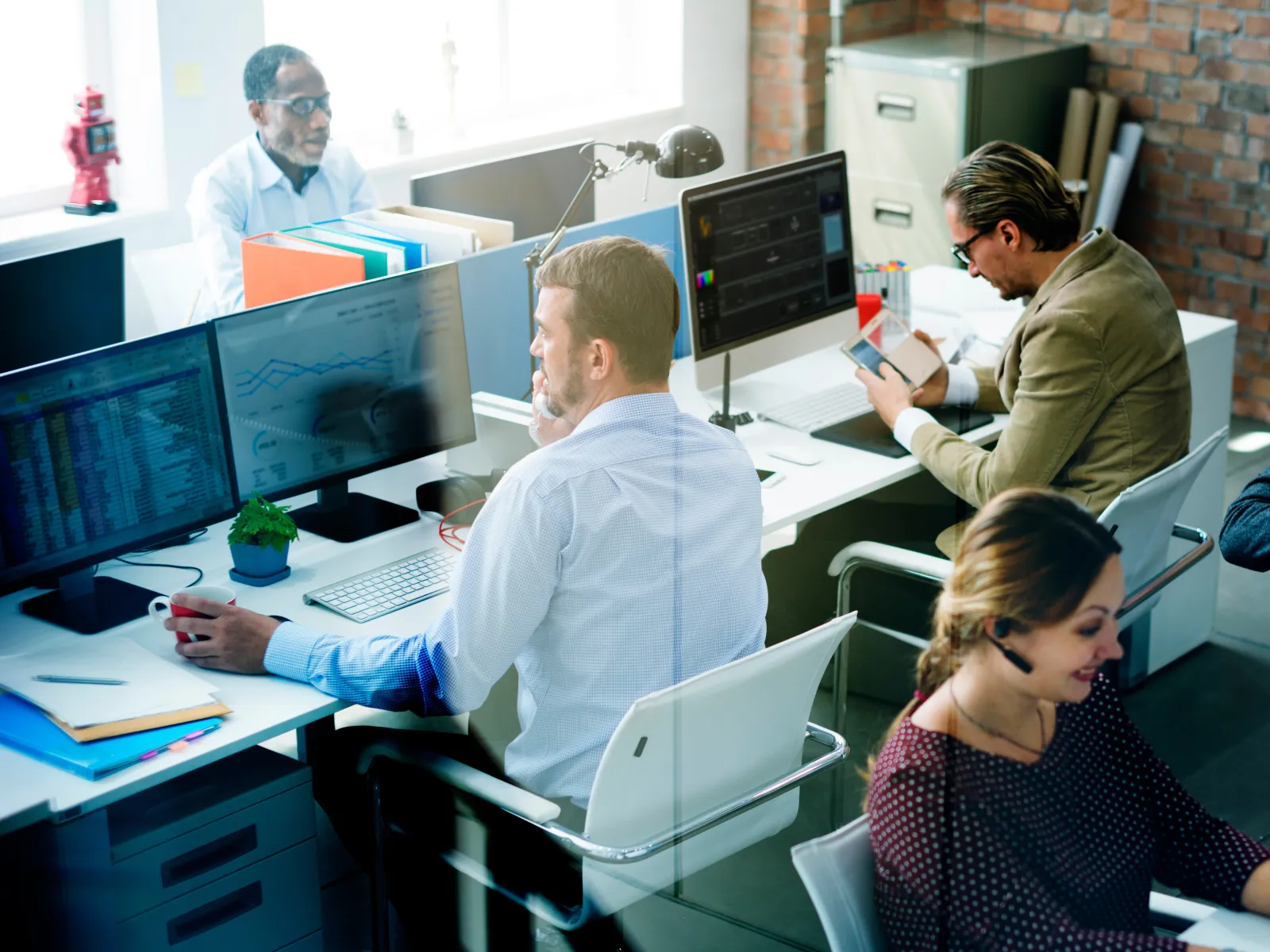 Busy office scene with professionals working at computers and talking on phones in a modern workspace