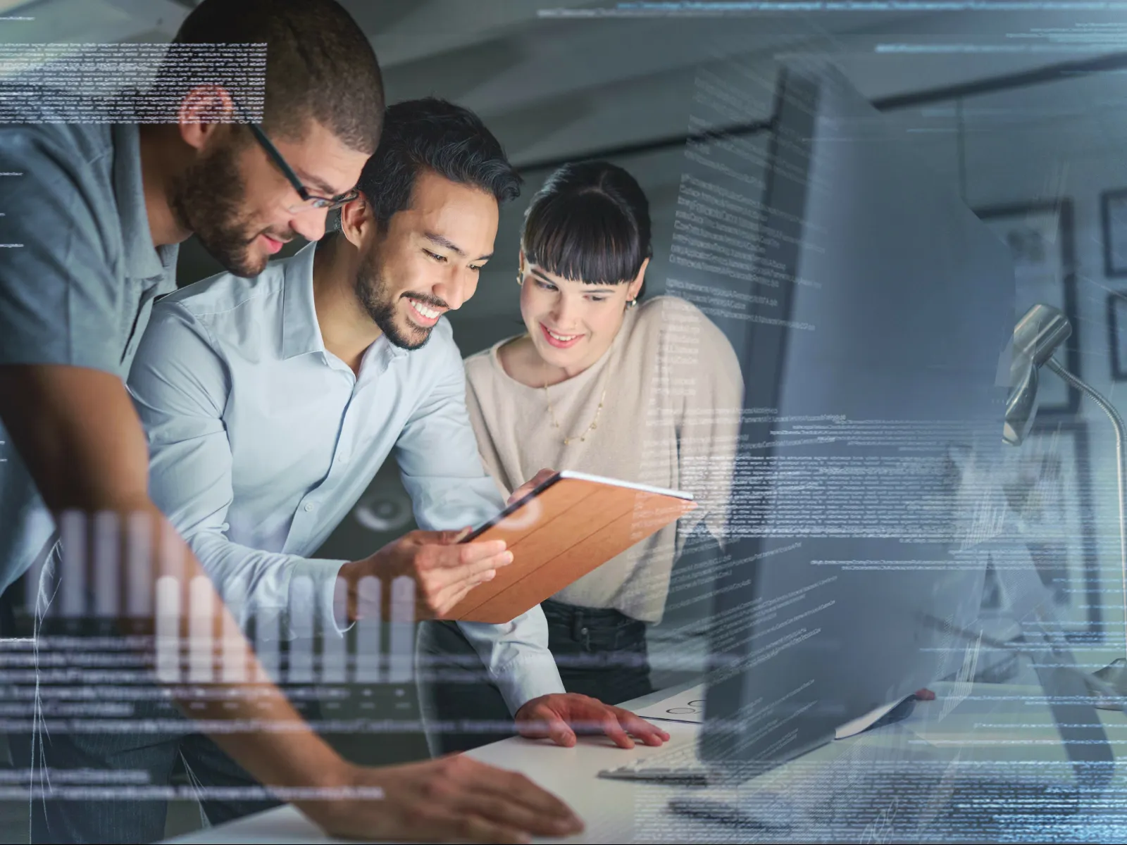 Three young professionals collaborating over a digital tablet with transparent code overlays in an office setting.