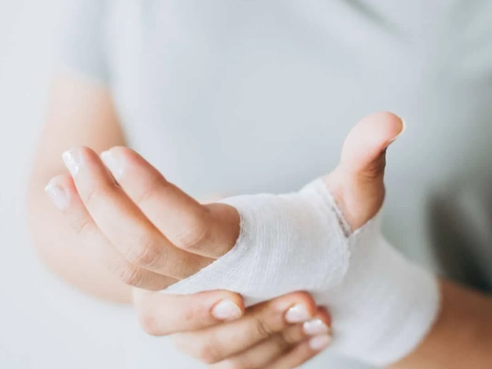 Close-up of a person's hand wrapped in white gauze bandage indicating injury or healing process.