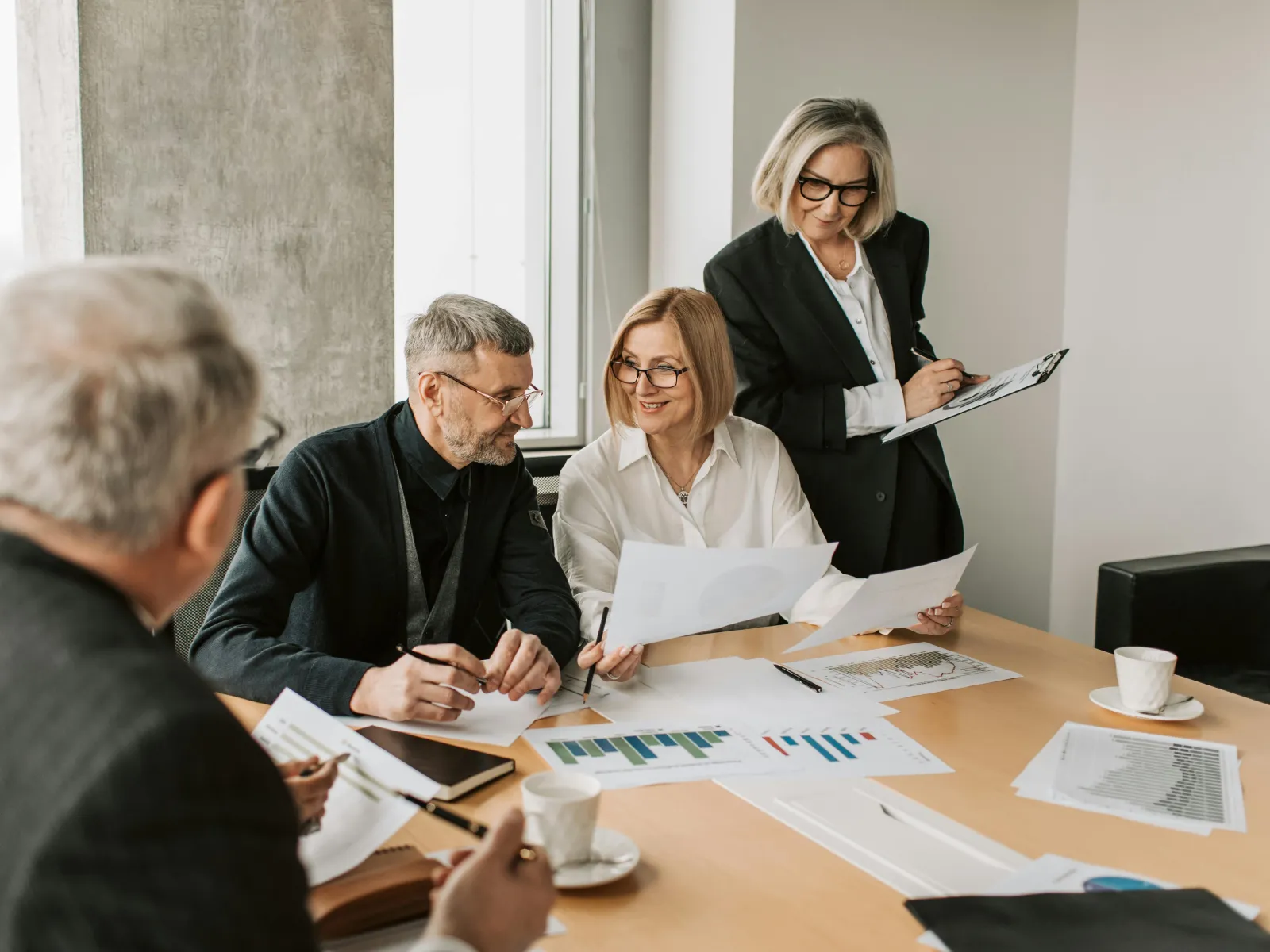 Business team reviewing charts and documents around a conference table in a modern office setting