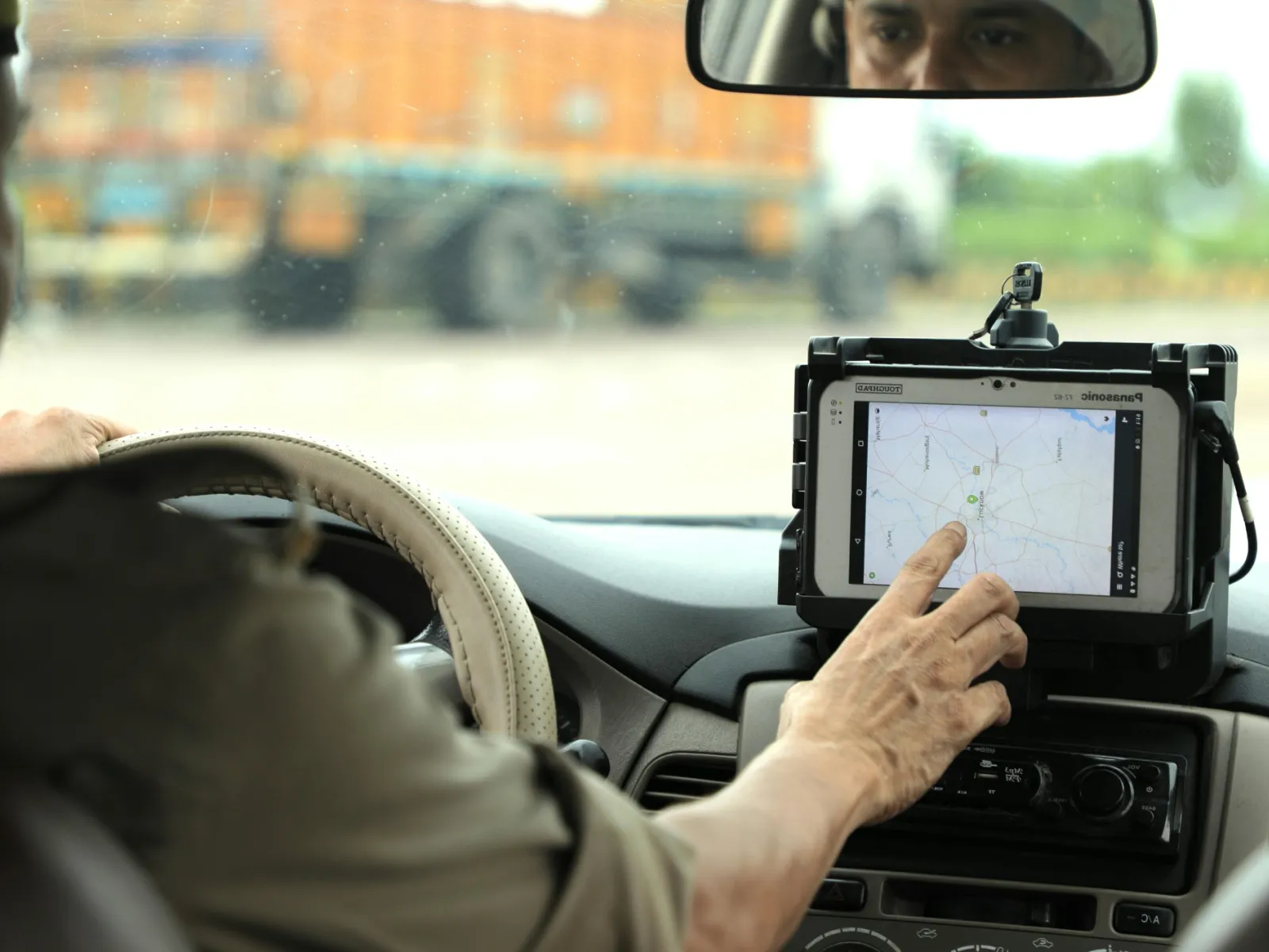 Driver using touchscreen GPS navigation device inside a vehicle while holding steering wheel