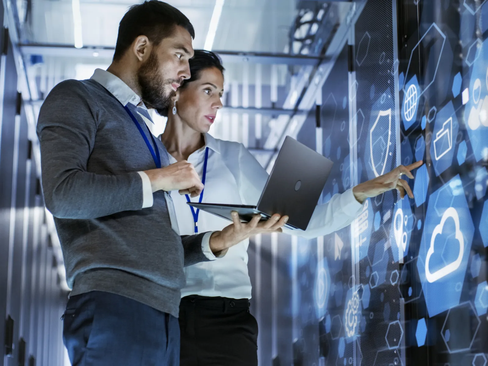 Two professionals analyzing digital data on a screen in a tech environment.