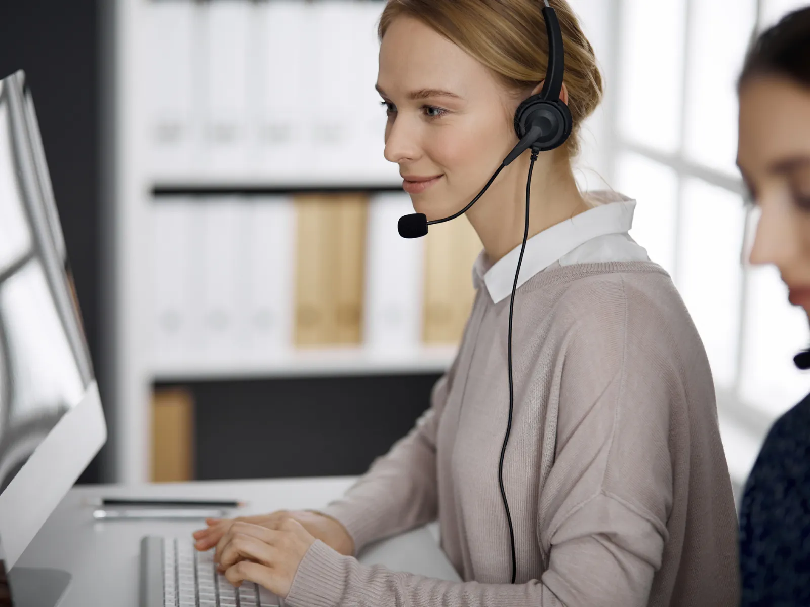 Customer service representative assisting clients in a modern office environment.