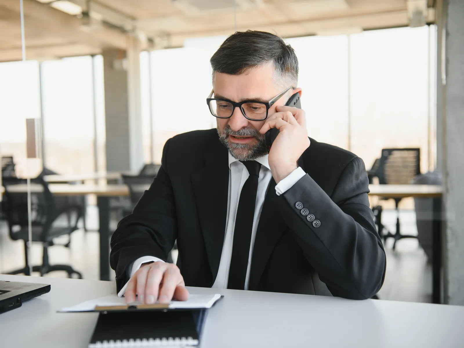 a man sitting at a desk with a laptop and a phone