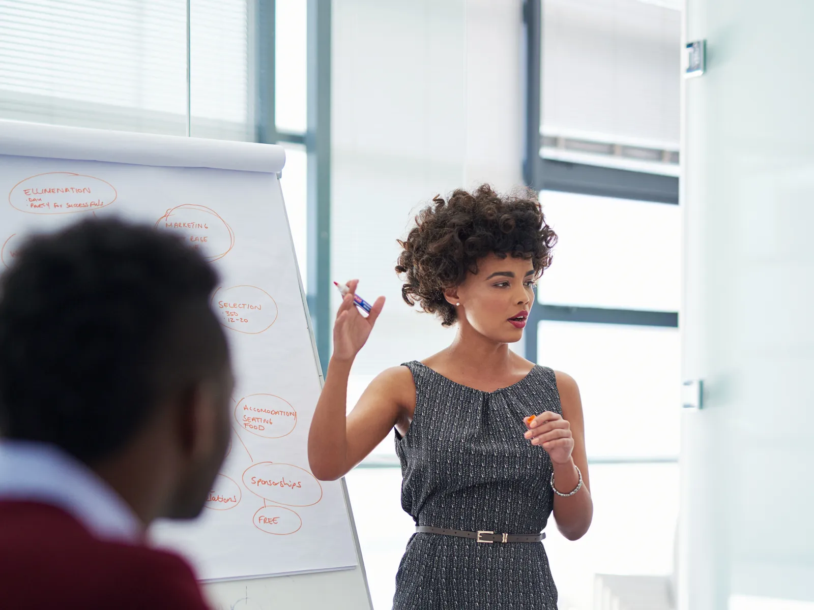 a woman standing in front of a man and a whiteboard