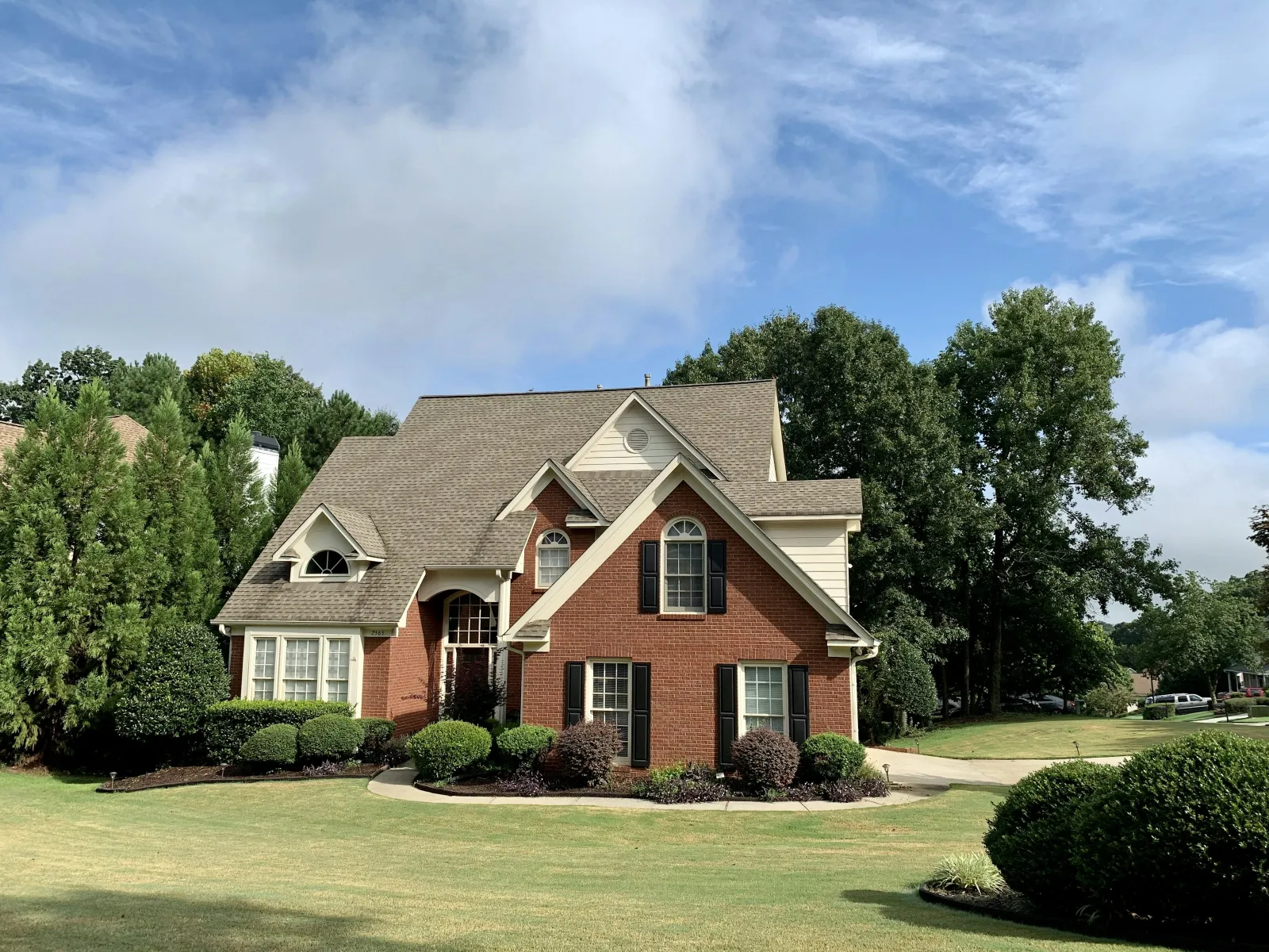 a brick house with a lawn and trees in the front