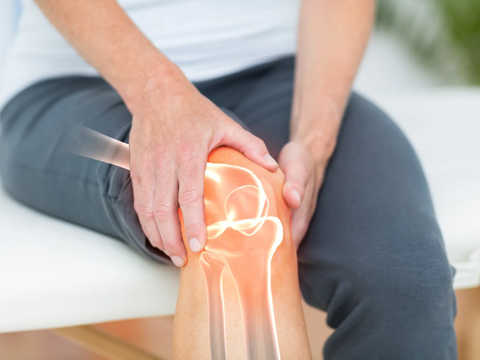 Person holding their knee with highlighted bone and joint pain illustration overlay.
