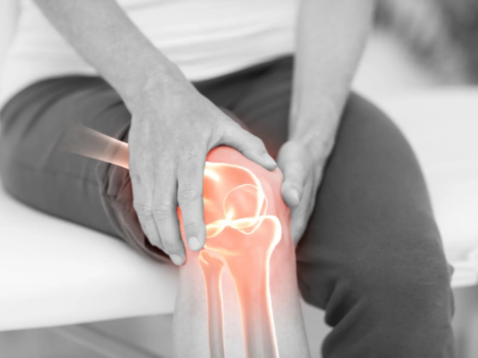 Person holding painful knee with glowing highlighted bones indicating joint pain or injury