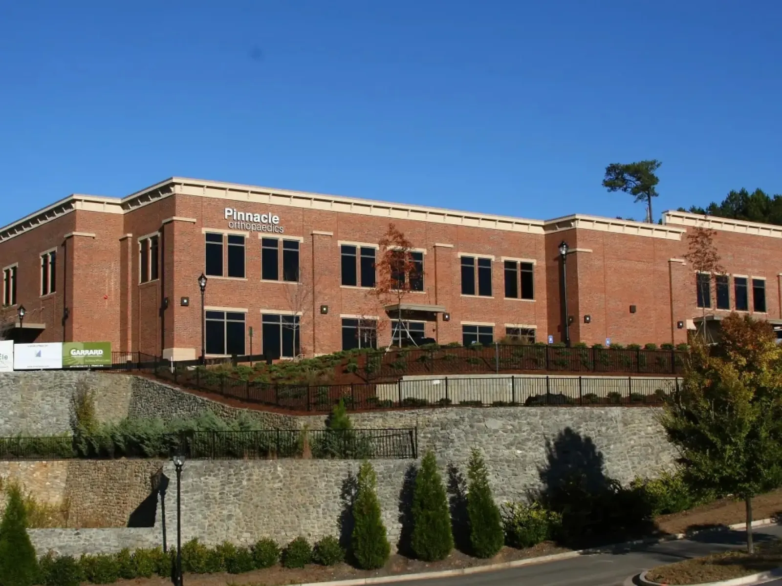 Modern two-story brick building of Pinnacle Orthopaedics under clear blue sky with landscaped greenery