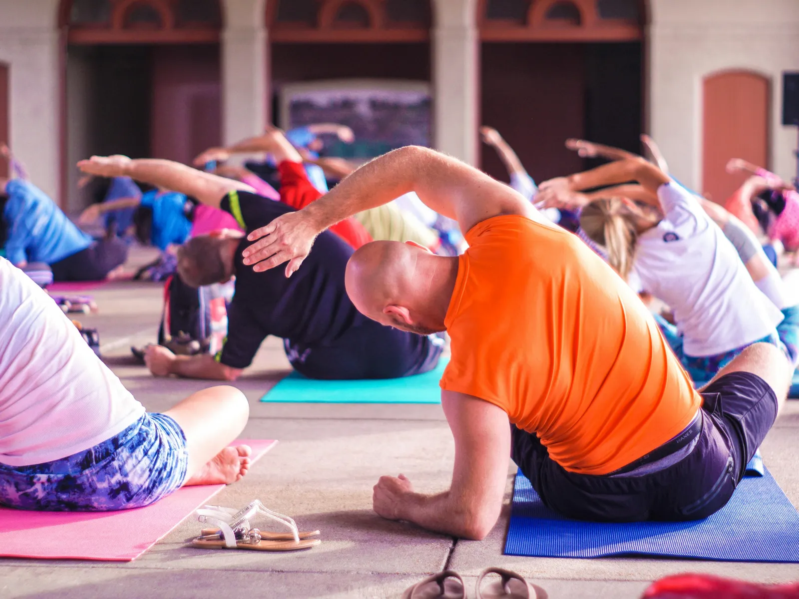 Group of people stretching side body muscles on mats during an indoor fitness or yoga class.