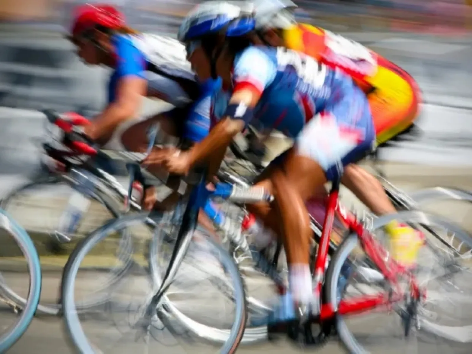 Motion-blurred cyclists racing closely on road bikes during a competitive cycling event