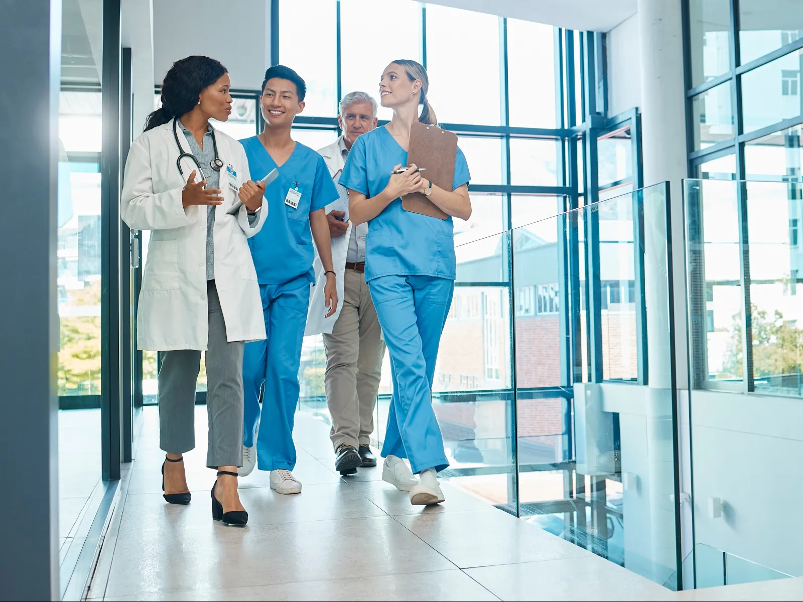 Medical team including a doctor and nurses walking and discussing inside a modern hospital corridor.