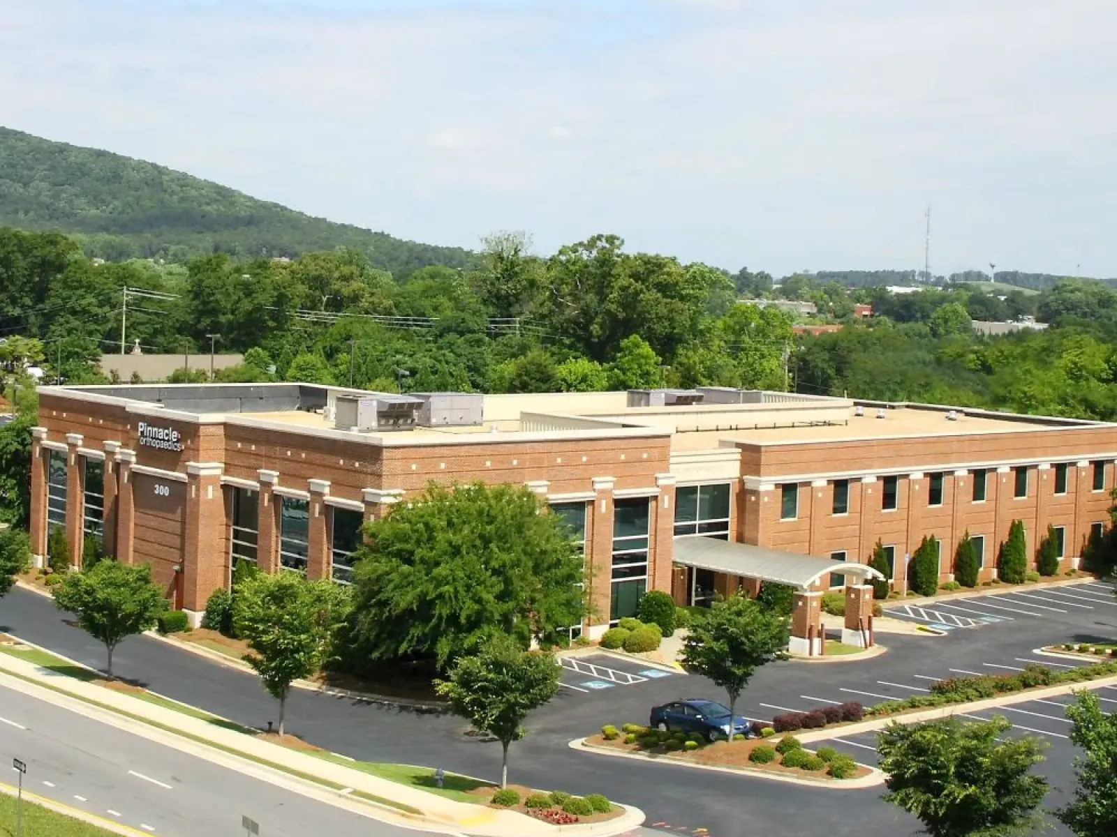 Two-story brick medical office building with Pinnacle Orthopaedics signage surrounded by trees and parking lots.