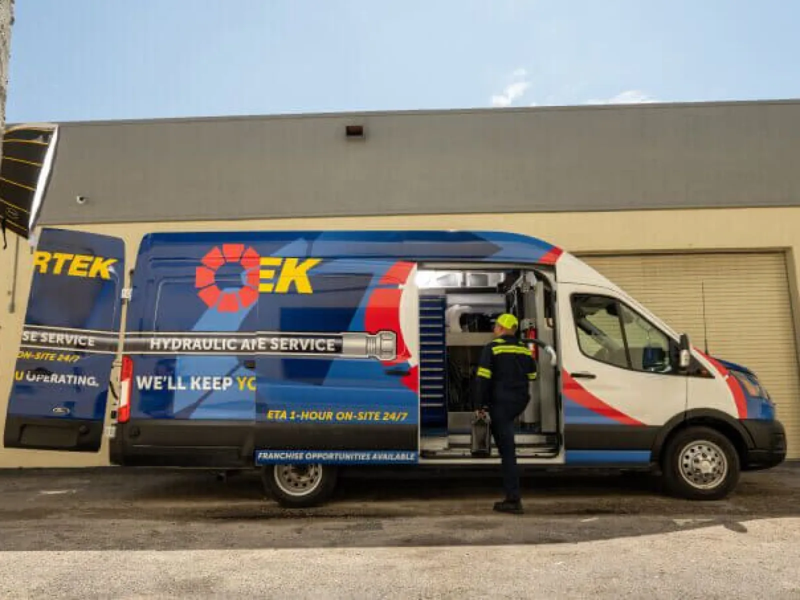Blue and white hydraulic APE service van with open side door and technician standing outside in uniform.