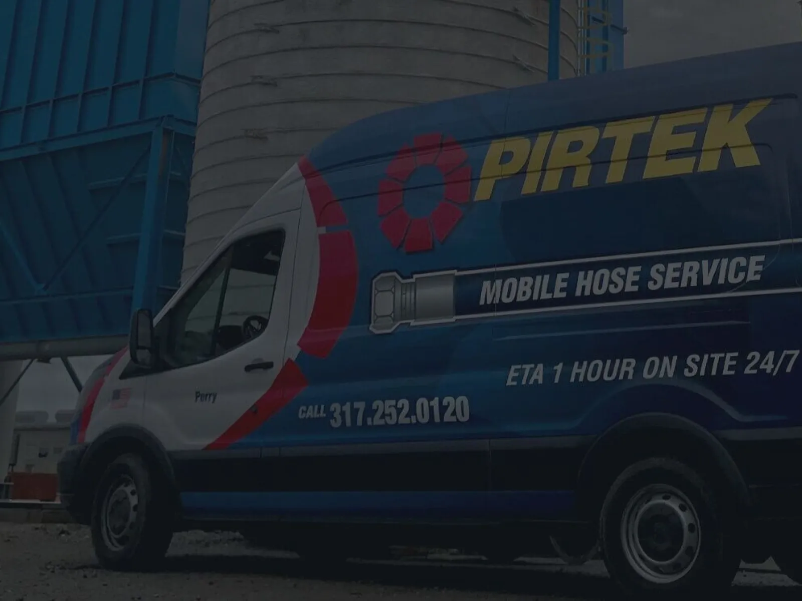 Pirtek branded mobile hose service van parked at an industrial site near large blue equipment.