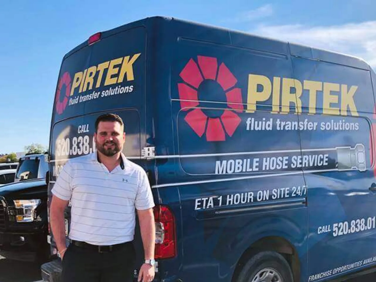 Man standing next to a blue Pirtek service van advertising mobile hose service and 24/7 on-site ETA.