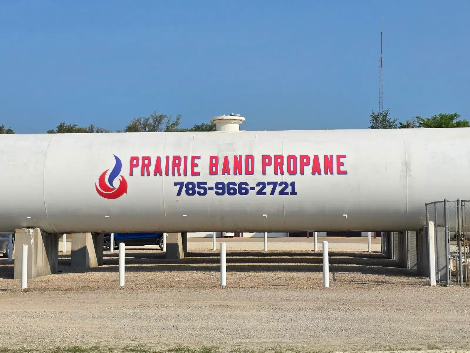Large white propane storage tank labeled Prairie Band Propane with contact number in an outdoor setting.