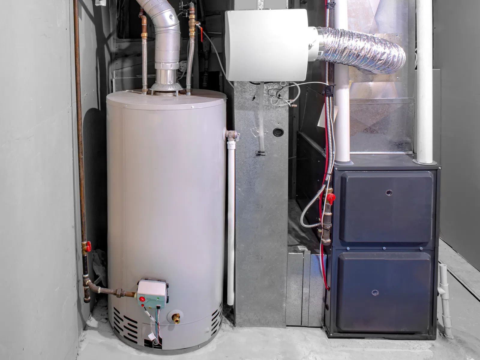 Modern water heater and furnace system installed in a clean basement utility room with pipes and ducts