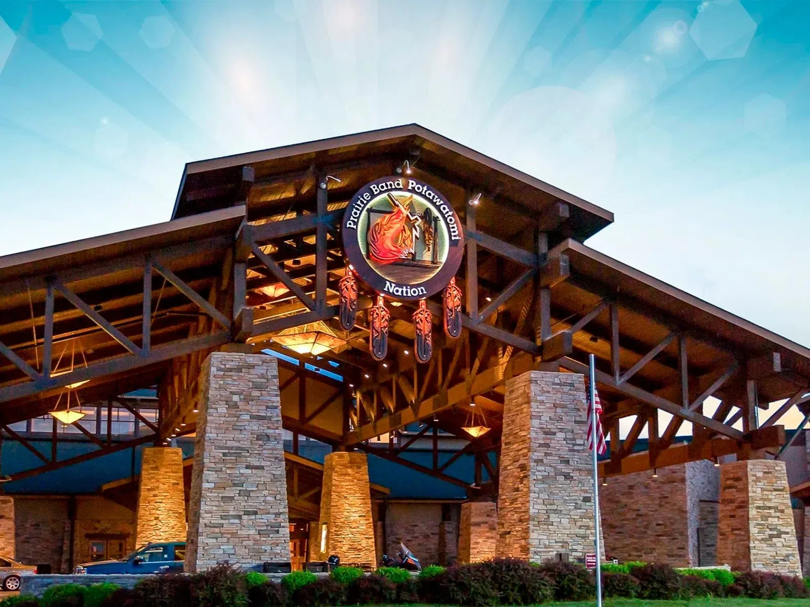 Entrance of Potawatomi Nation casino with stone pillars and wooden roof structure at dusk under a blue sky.