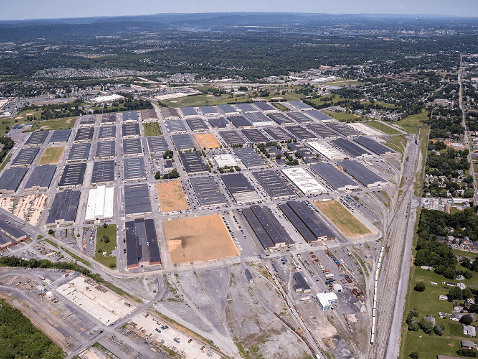 Aerial view of a large industrial complex with numerous warehouse buildings and surrounding rail tracks.