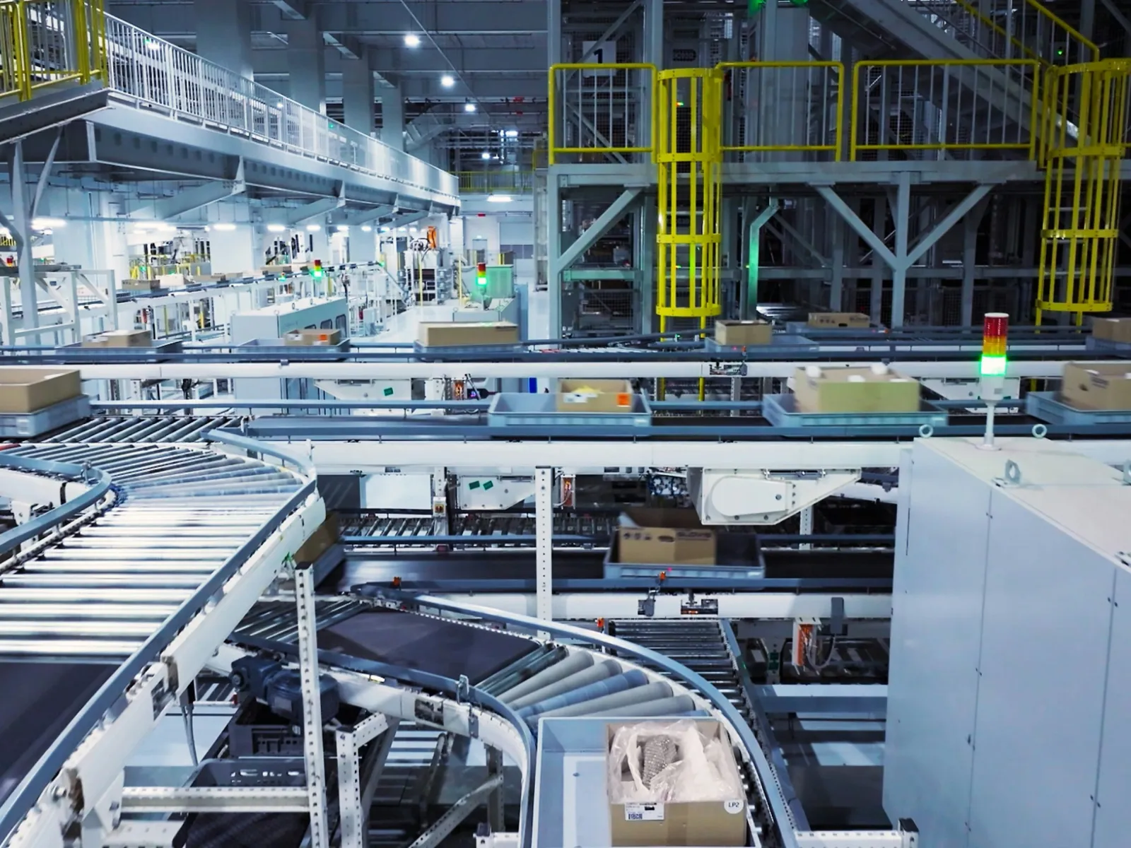 Automated conveyor belts transporting boxes inside a large modern warehouse with metal structures and equipment.