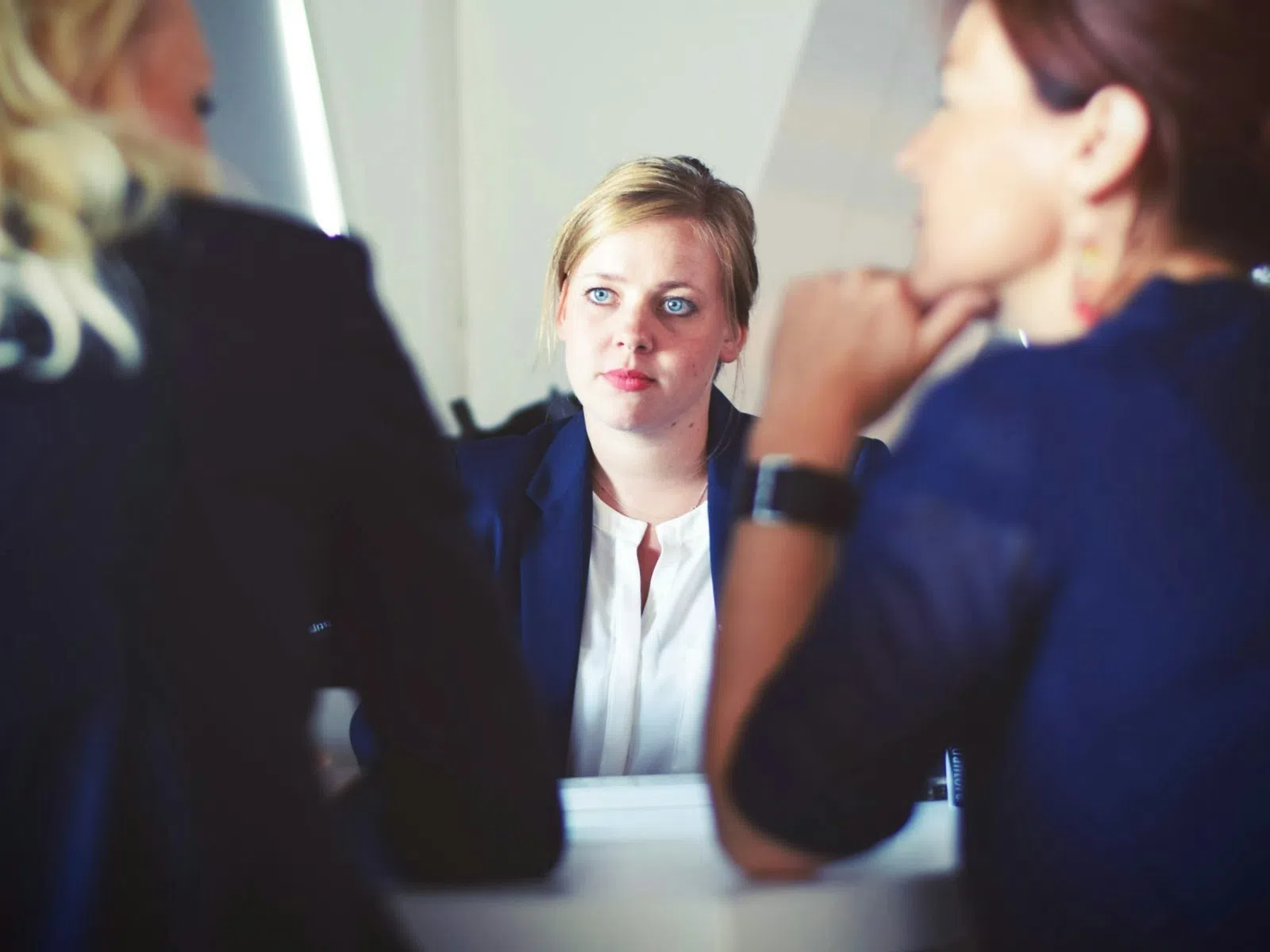Young professional woman attentively listening during a business meeting with two colleagues in a modern office.