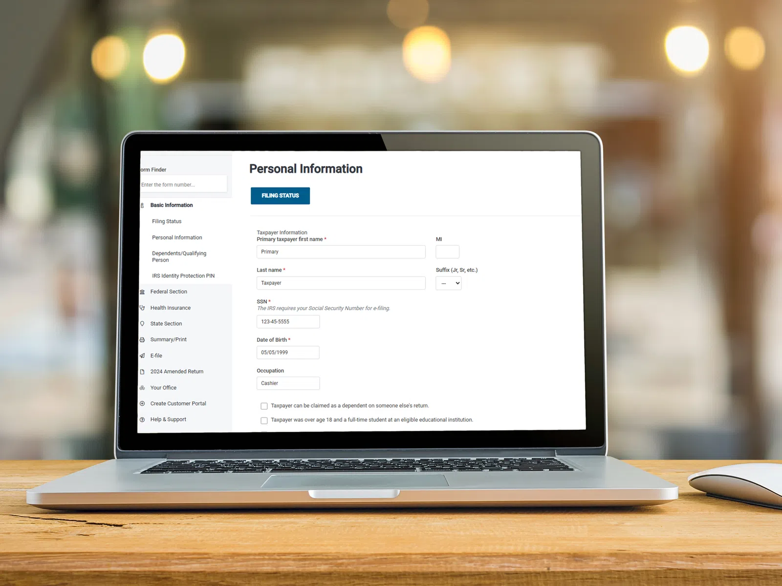 Laptop displaying a personal information form for tax filing with fields like name, SSN, and date of birth on screen.