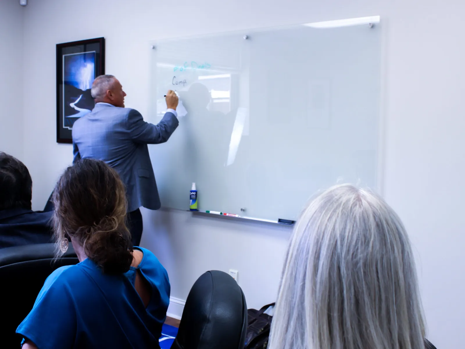 Businessman writing on whiteboard during a meeting with colleagues in a conference room