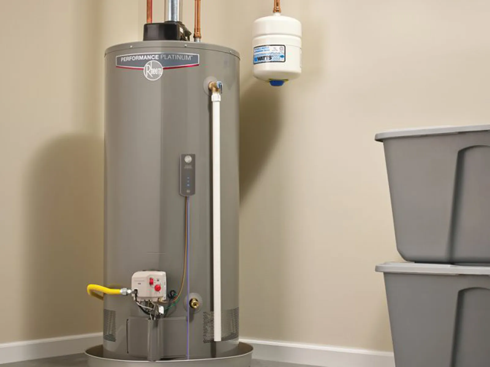 Rheem Performance Platinum water heater installed in a utility room with storage bins nearby.