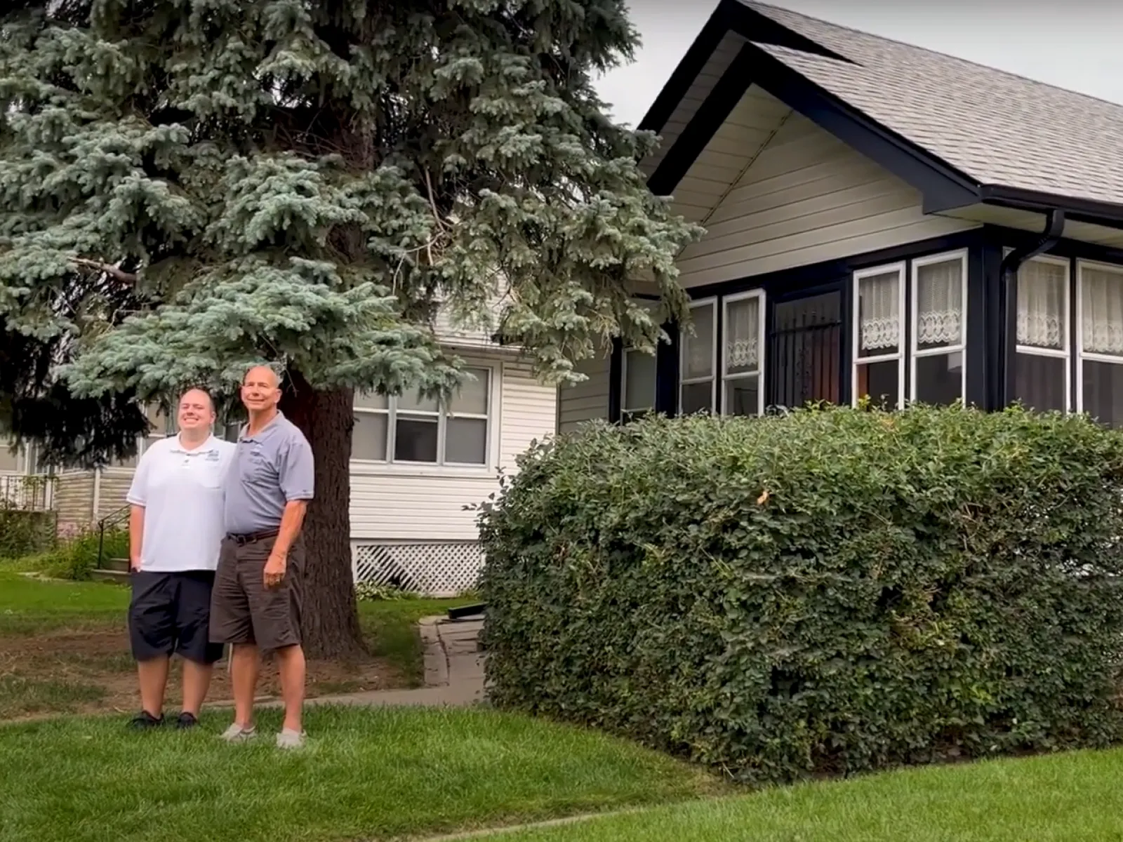 two men standing in front of a house