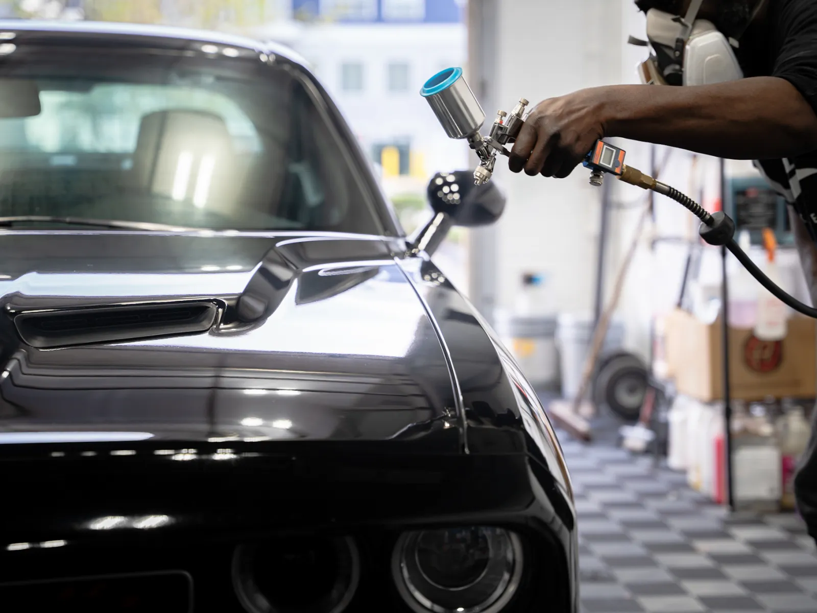 a person ceramic coating a car with a spray gun