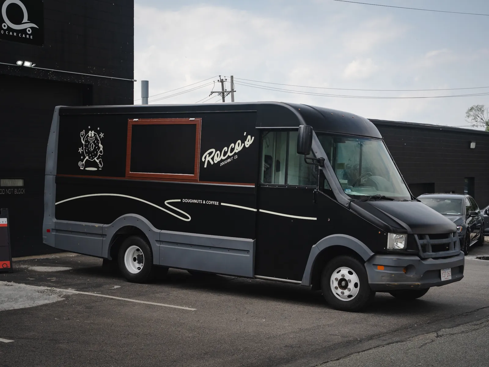 Black Rocco's food truck parked outside with logo and doughnuts and coffee text on side panel.
