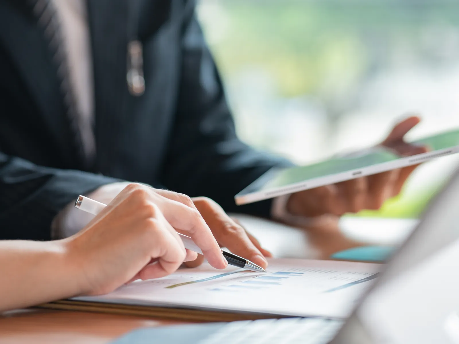 Business professionals analyzing financial charts with tablet and documents during meeting